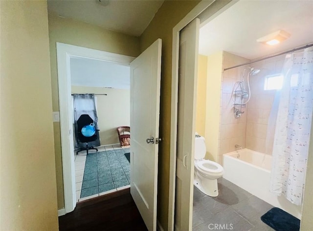 bathroom with tile patterned flooring, shower / bath combination with curtain, and toilet