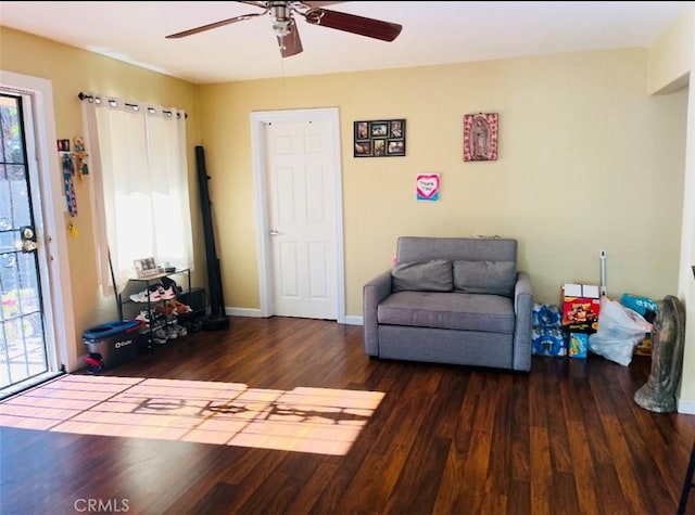 living area with ceiling fan and dark hardwood / wood-style flooring