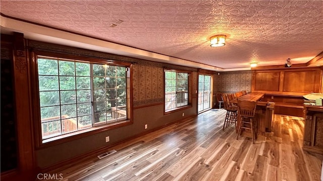 dining space with wood-type flooring, a textured ceiling, and indoor bar