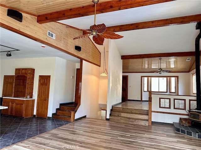 unfurnished living room featuring ceiling fan, dark hardwood / wood-style floors, a wood stove, and wood ceiling