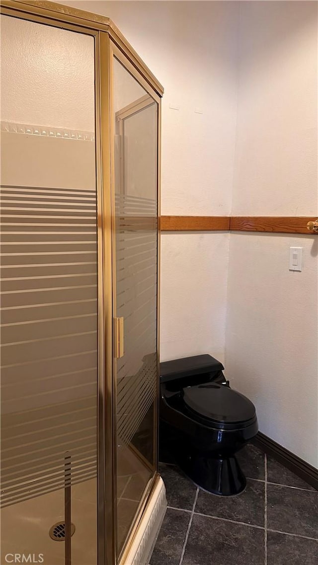 bathroom featuring toilet, tile patterned floors, and a shower with shower door