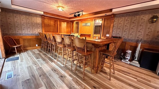 bar featuring a textured ceiling and light hardwood / wood-style flooring