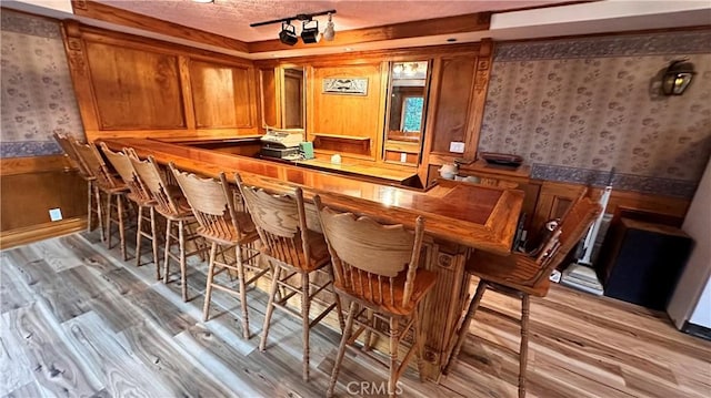 bar with light hardwood / wood-style floors and a textured ceiling