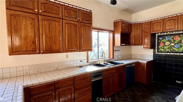 kitchen with dishwasher, tile countertops, dark tile patterned floors, and sink