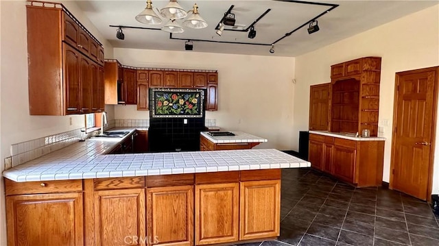 kitchen with tile countertops, decorative light fixtures, kitchen peninsula, and sink