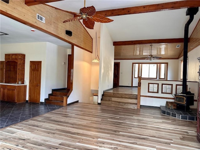 unfurnished living room with hardwood / wood-style floors, ceiling fan, a wood stove, and high vaulted ceiling