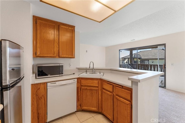 kitchen featuring sink, kitchen peninsula, a textured ceiling, light carpet, and appliances with stainless steel finishes