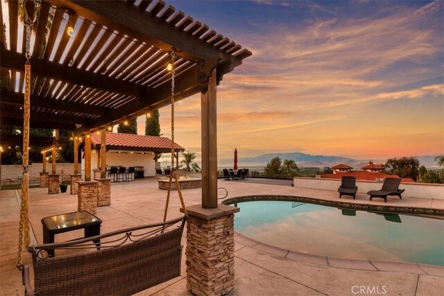 pool at dusk with a pergola and a patio area