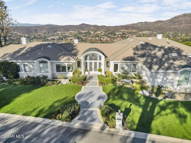 ranch-style home featuring a mountain view, french doors, and a front lawn