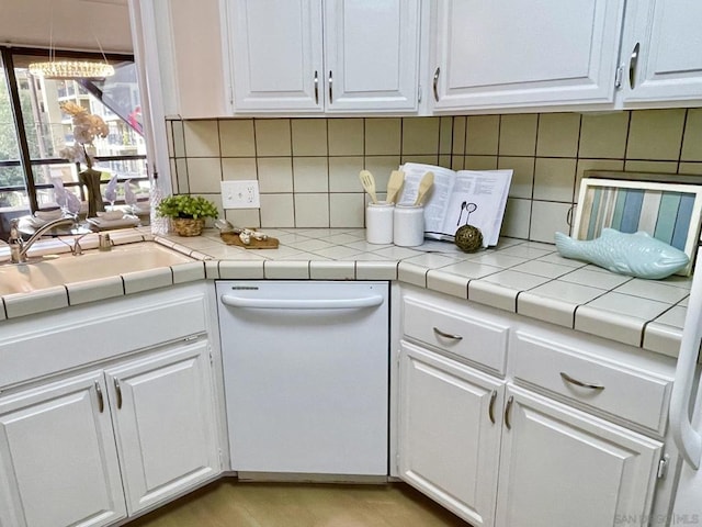 kitchen with dishwasher, white cabinets, and tile counters