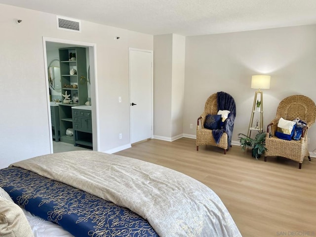 bedroom with hardwood / wood-style flooring and ensuite bath