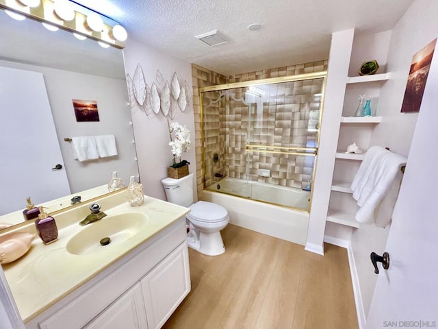 full bathroom featuring bath / shower combo with glass door, a textured ceiling, toilet, vanity, and hardwood / wood-style flooring