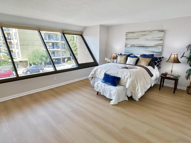 bedroom with light hardwood / wood-style floors and a textured ceiling