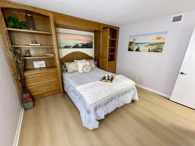 bedroom featuring light hardwood / wood-style floors and a textured ceiling