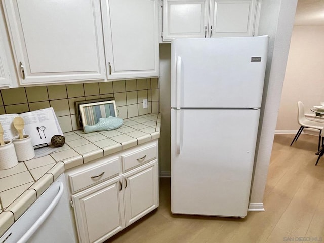 kitchen with decorative backsplash, white cabinetry, tile counters, and white refrigerator