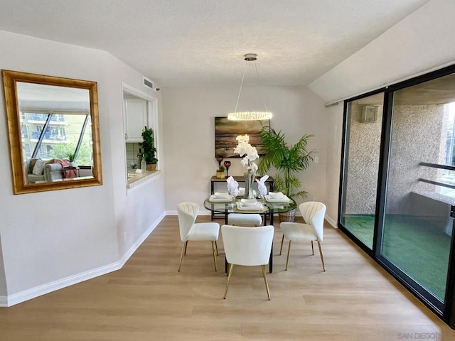 dining room with wood-type flooring, vaulted ceiling, and a notable chandelier