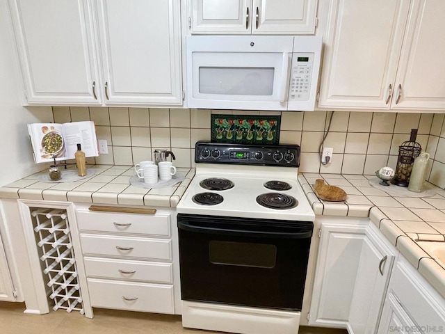 kitchen with tile countertops, white appliances, tasteful backsplash, and white cabinetry