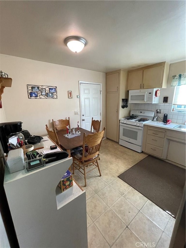 kitchen with tasteful backsplash, light tile patterned floors, sink, and white appliances