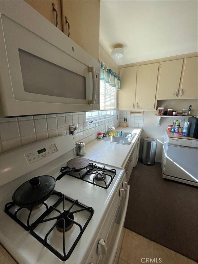 kitchen featuring light tile patterned floors, backsplash, sink, and white appliances