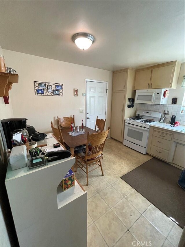 kitchen featuring light tile patterned floors, backsplash, and white appliances