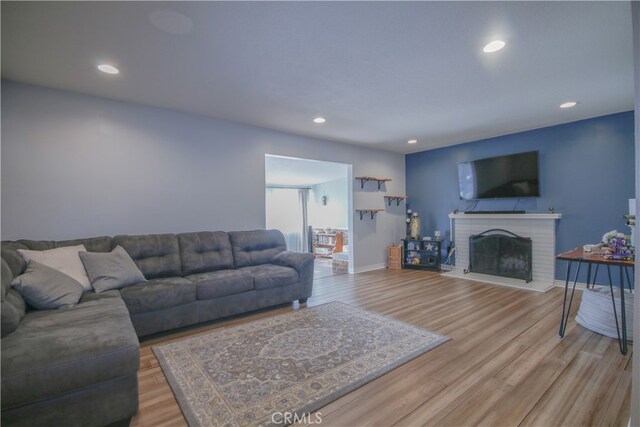 living room featuring a brick fireplace and light wood-type flooring