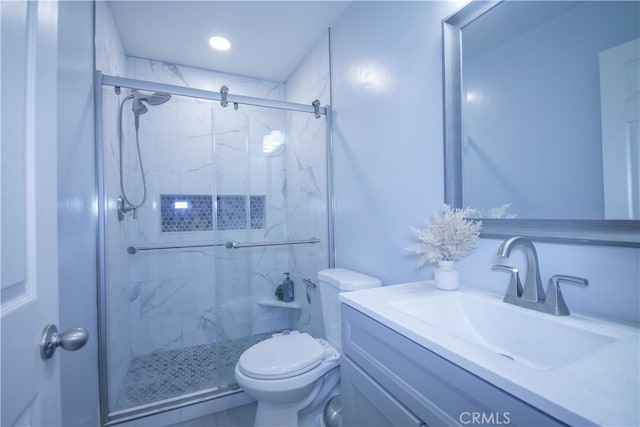 bathroom featuring a shower with door, toilet, and vanity