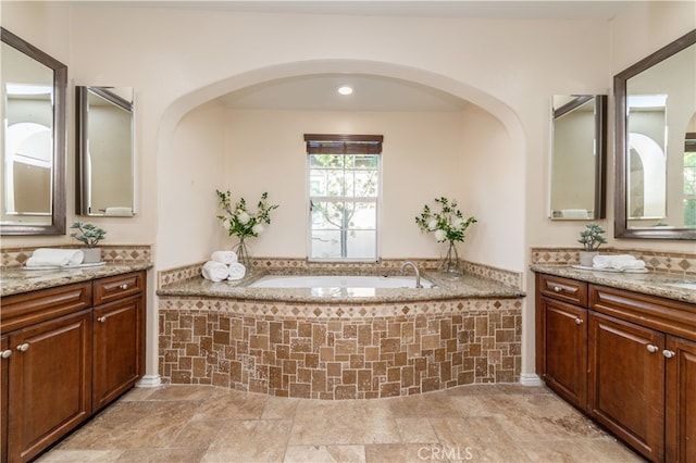 bathroom with tiled tub and vanity