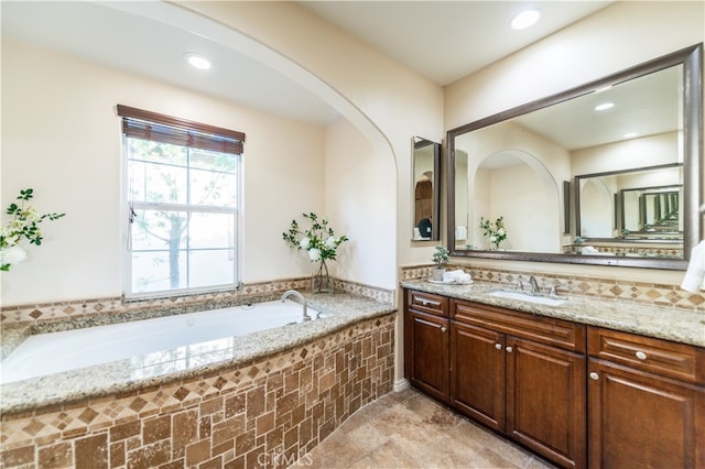 bathroom featuring tile patterned flooring, vanity, and tiled bath