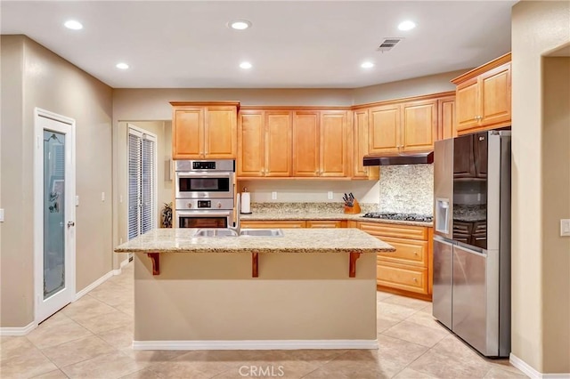 kitchen featuring a breakfast bar, an island with sink, and appliances with stainless steel finishes