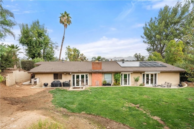 back of house with french doors and a yard