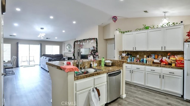 kitchen featuring white cabinetry, stainless steel dishwasher, vaulted ceiling, and light wood-type flooring