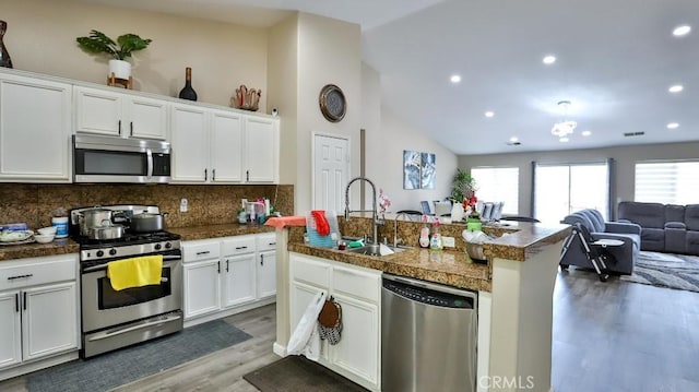 kitchen with white cabinetry, sink, a kitchen island with sink, appliances with stainless steel finishes, and hardwood / wood-style flooring