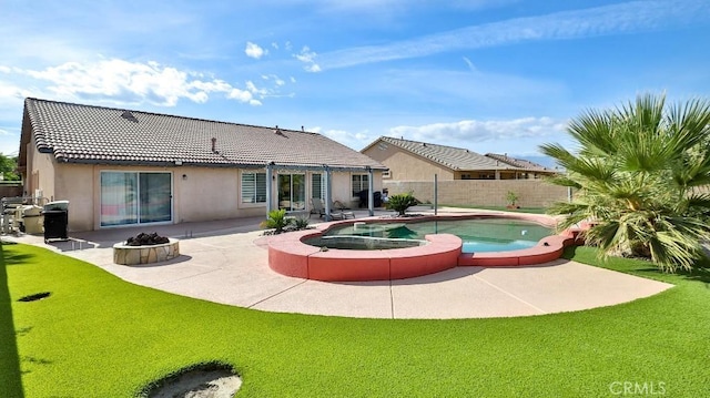 back of property with a swimming pool with hot tub, a patio, and a lawn