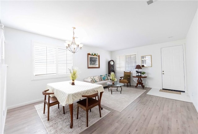 dining space featuring a chandelier, a wealth of natural light, and light hardwood / wood-style flooring