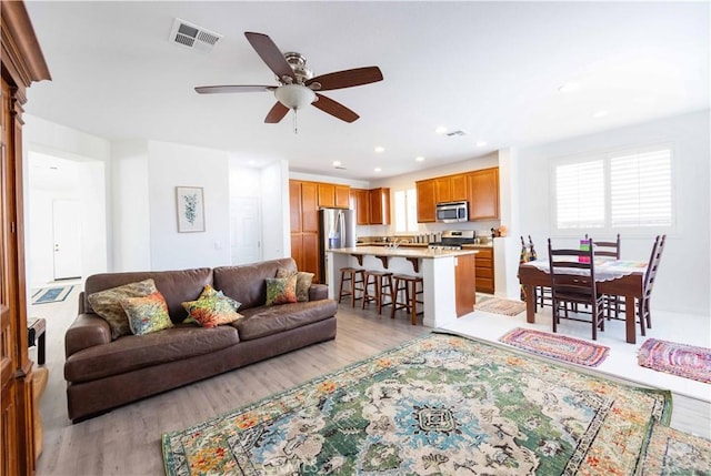 living room with ceiling fan and light hardwood / wood-style flooring