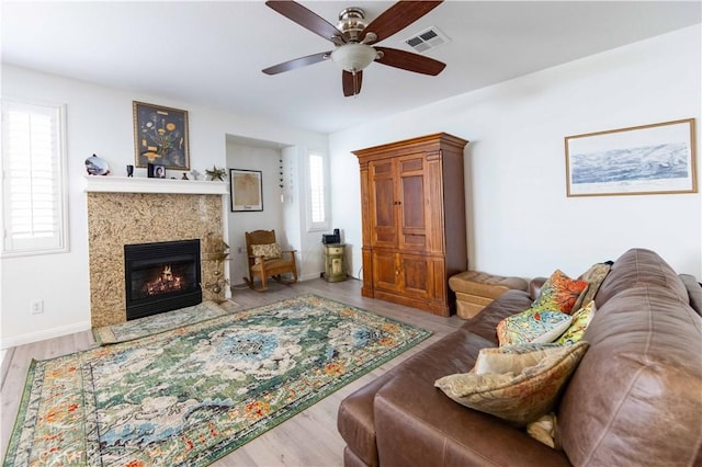 living room featuring hardwood / wood-style floors, ceiling fan, and a premium fireplace