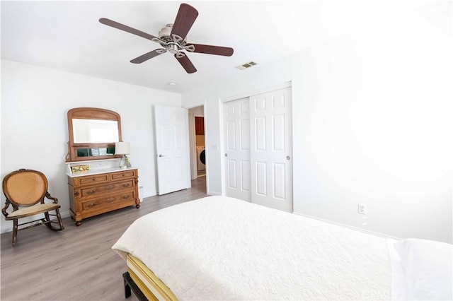 bedroom featuring ceiling fan, light hardwood / wood-style floors, washer / clothes dryer, and a closet