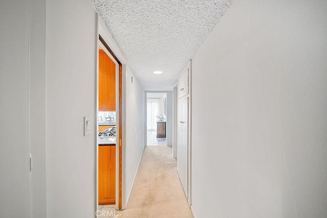 corridor featuring light carpet and a textured ceiling