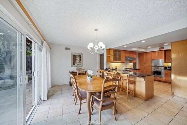 tiled dining room featuring a textured ceiling and an inviting chandelier