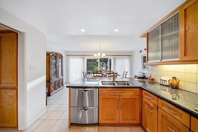 kitchen featuring sink, an inviting chandelier, stainless steel dishwasher, decorative backsplash, and light tile patterned floors