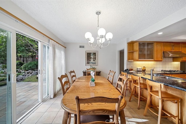 dining room featuring a textured ceiling, a notable chandelier, light tile patterned floors, and sink