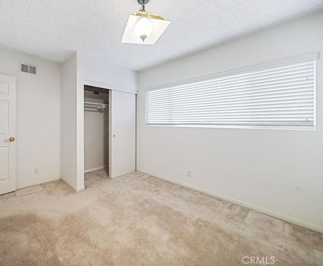 unfurnished bedroom featuring a textured ceiling, light carpet, and a closet