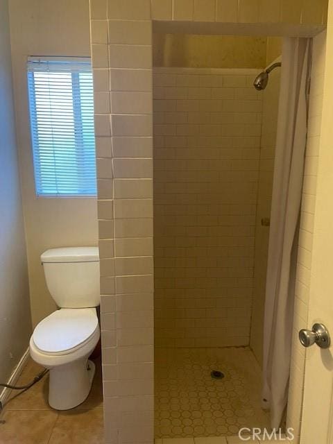 bathroom featuring tiled shower, tile patterned flooring, and toilet