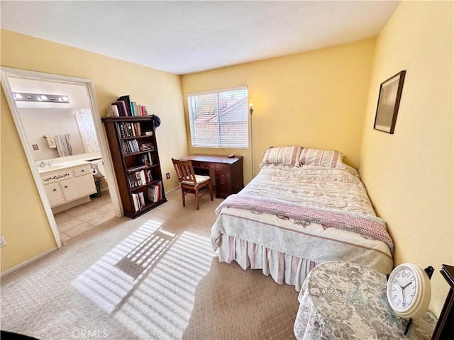 bedroom with light colored carpet, ensuite bathroom, and a sink