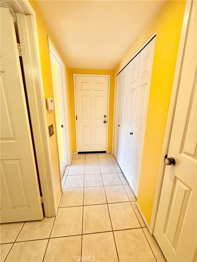 hall featuring light tile patterned floors and baseboards