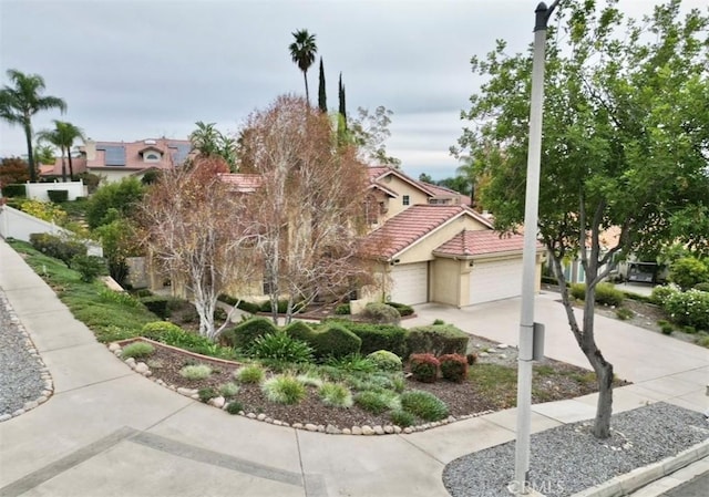 view of front facade with concrete driveway, a tiled roof, a garage, and stucco siding