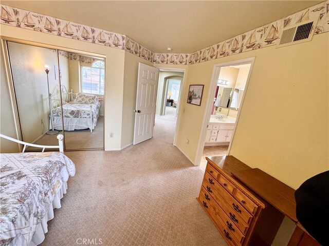 bedroom featuring baseboards, visible vents, carpet floors, ensuite bath, and a closet