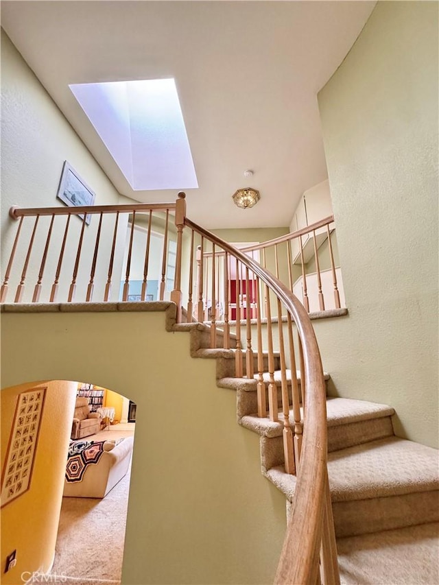 staircase with a skylight and carpet floors