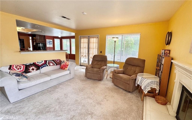 living area with a premium fireplace, light colored carpet, and visible vents