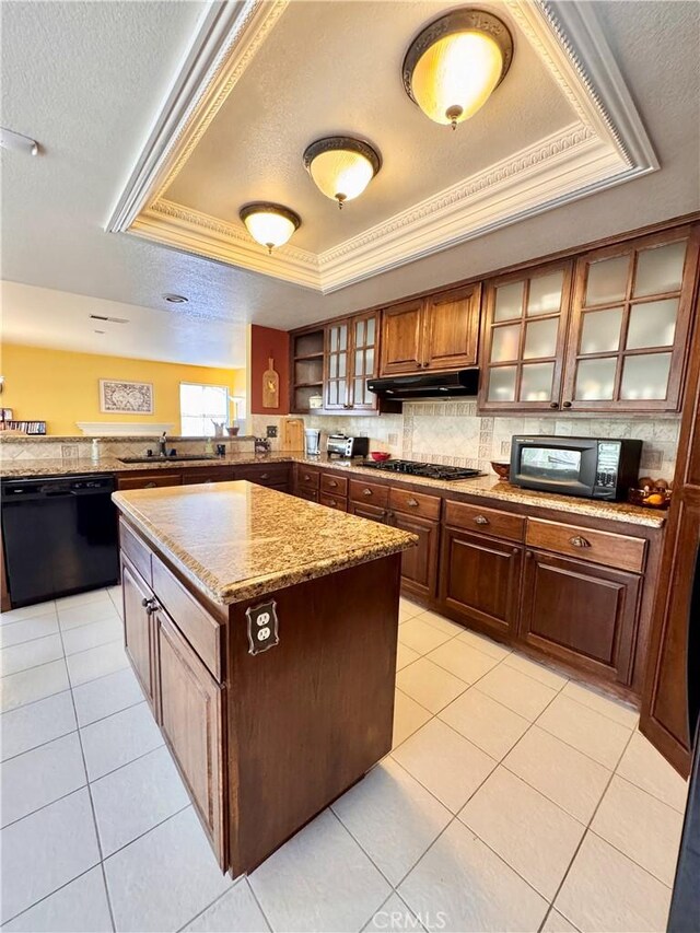 kitchen featuring black appliances, under cabinet range hood, a textured ceiling, a raised ceiling, and tasteful backsplash